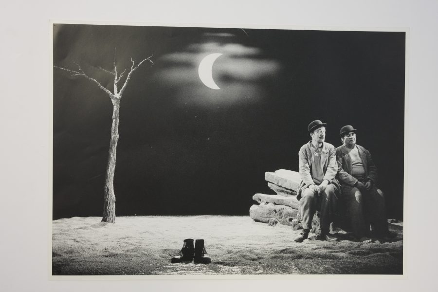 Fotokopia av ett svartvitt foto av två män sittandes på en steg, ett par skor i mitten och ett träd till vänster och en måne