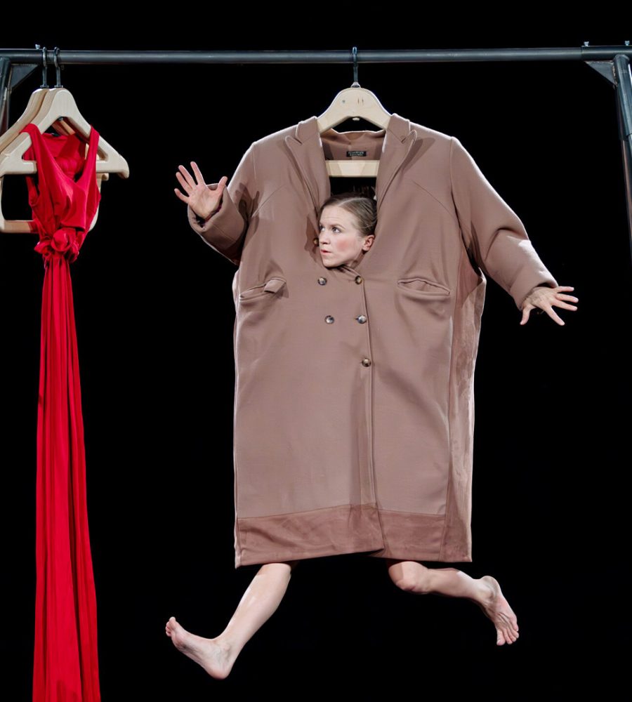 En akrobat i en stor rock som hänger i en klädställning